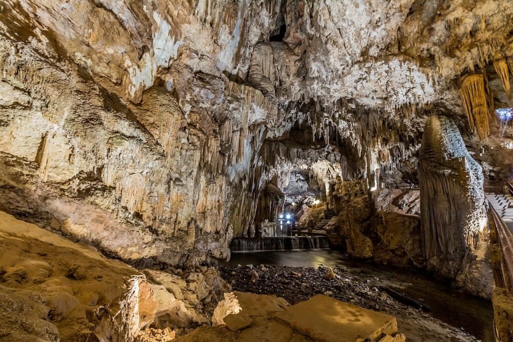 Interior da Caverna do Diabo mostrando imensas colunas calcíticas e diversas formações rochosas iluminadas, criando um ambiente místico e espetacular.