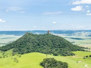 Vista panorâmica da formação rochosa Pedra de Torrinha, uma das principais atrações turísticas da cidade de Torrinha, com paisagens verdejantes e céu azul ao fundo, ideal para atividades ao ar livre e esportes de aventura.